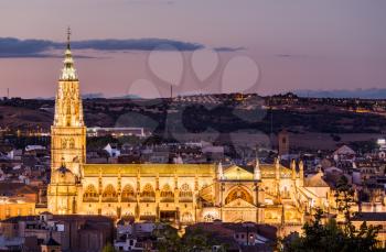 Dusk cityscape at dusk as the flood lights are illuminated on cathedral in ancient city of Toledo, Spain, Europe