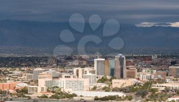 Downtown area of Tucson in Arizona with the sun lighting the buildings while storm clouds gather over distant mountain range