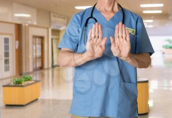 Senior caucasian doctor in scrubs in hospital refusing entry  for treatment