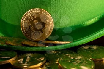Treasure of golden bitcoins inside a green velvet hat on wooden table to celebrate luck on St Patrick's Day of March 17th