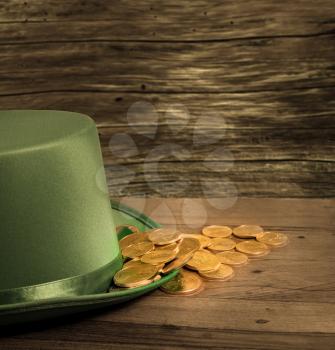 Treasure of pure gold coins inside the rim of a green velvet hat. Placed on wooden table to celebrate luck on St Patrick's Day on March 17th
