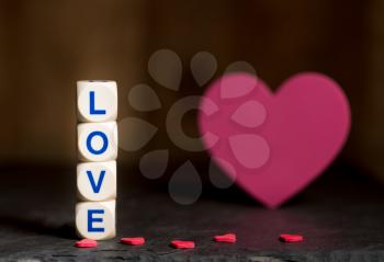 Love spelled in wooden blocks with heart shaped cutouts for Valentines day with copy space
