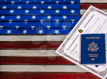 USA passport and Naturalization Certificate of citizenship over background of a wooden US Stars and Stripes flag