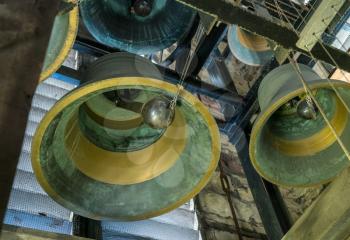 View into interior of large brass church bell in stone tower with pulley and bell clapper