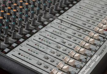 Sound mixing board with focus on the audio sliders for level from musical instruments