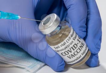 Covid-19 coronavirus vaccine with hypodermic syringe needle being inserted into the vaccination bottle