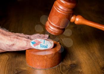 I voted campaign sticker on senior hand with mallet and gavel to illustrate the concept of judges overruling the rights of voters in the election
