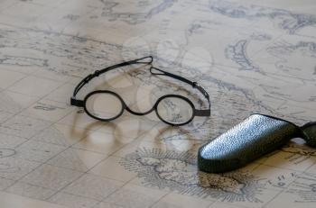 Pair of round magnifying spectacles on top of old sea faring map