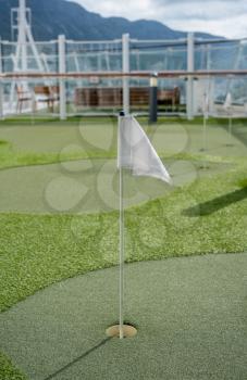 Small artificial putting green for golf practice on the deck of a cruise ship