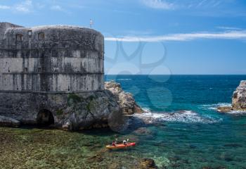 Kayakers or canoeists in the sea by the city walls and old fort Lawrence in Dubrovnik