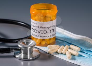Prescription bottle and capsules illustrating trials of oral antiviral treatment for SARS-CoV-2 or Covid-19 virus