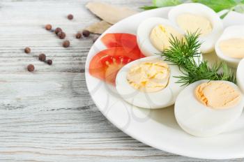 Boiled hen eggs in a white plate on a wooden background