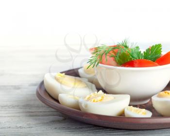 Boiled hen eggs in a clay dish on a wooden background