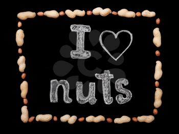Frame of peanuts on a black background and chalk inscription I love nuts