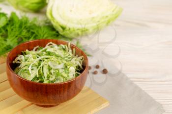 Fresh vegetable salad with cucumber and white cabbage in a wooden plate.  Vegetarian and healthy diet food concept. 