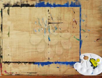 wooden easel with art palette on empty canvas