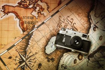 The old classic film camera lies on two maps of the world