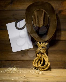Cowboy accessories hanging on old wooden ranch wall and blank white background for text