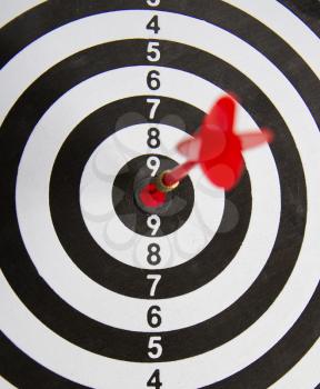 Close-up dart board with a red arrow that hit the center of the target