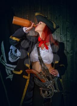 Young Attractive Armed Girl Pirate Captain Drinks Clay Bottle Alcohol Jolly Roger Flag Background