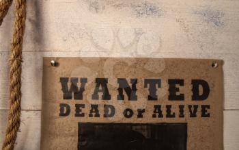 old paper criminal wanted list on yellowed paper pinned to a rough wooden wall