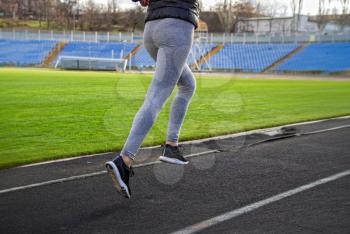 young girl in sportswear jogging through a deserted stadium