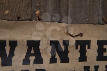 old poster with wanted posters nailed to a rough wooden wall close-up