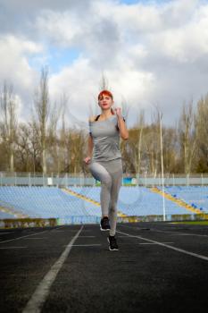 young girl in sportswear jogging through a deserted stadium