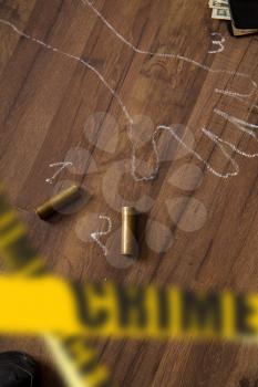 Crime scene fenced with yellow police tapes with a silhouette of the victim painted on the floor with chalk and brass sleeves from a hunting rifle.