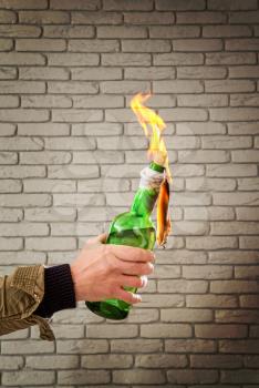Male hand holding a large burning bottle with molotov cocktail