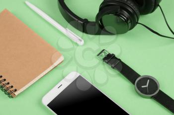 Smartphone, notepad, headphones, pen and watch on the blue background 