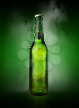 Cold wet beer bottle with frost and vapor on green background