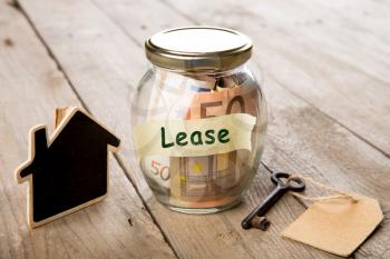 Real estate finance concept - money glass with Lease word and vintage key