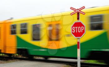 Fast move yellow regional train pass by railroad crossing.