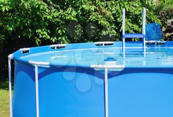 Circular water pool at garden with chlorine float and ladder.