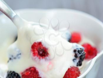 Blackberry and raspberry in the white yogurt with spoon.