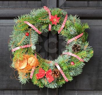 Christmas wreath with red ribbon and nut hanging on the door.