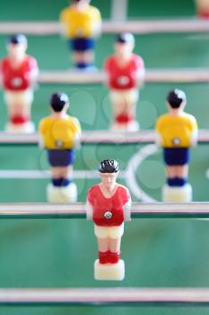 Closeup of the table football or foosball players in red and yellow jerseys.