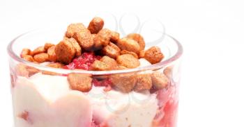 Curd cheese dessert with raspberries and small crunchies.