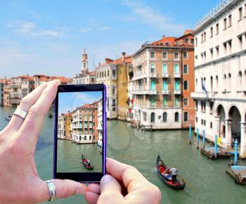 View over the mobile phone display during taking a picture of water canal in Venice. Holding the mobile phone in hands and taking a photo of Venice. Focused on mobile phone screen.