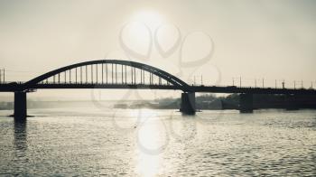 Sun reflection in the river with bridge in foggy background