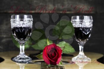 Red Rose and Wine Glasses Resting On Acoustic Guitar With Sign Lets Rock And Roll. Valentine's day concept