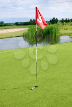 Golf field with red flag and ball
