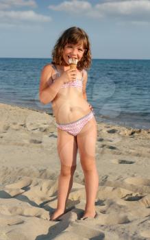 happy little girl eat ice cream on beach