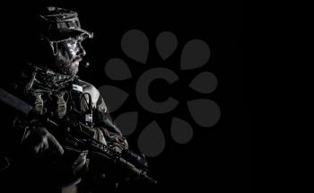 Bearded Special forces United States in Camouflage Uniforms studio shot half length black background. Holding weapons, wearing jungle hat, Shemagh scarf, he is ready to kill. Backlit