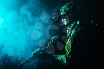 Security forces operator in Combat Uniforms with rifle, in the face of danger. Facing enemy, he is ready to fight. Studio contour silhouette shot, toned and colorized, backlight, profile side view