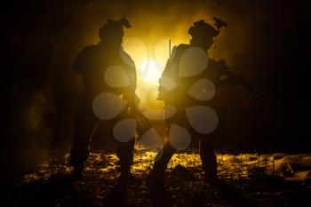Dark silhouettes of pair of soldiers moving in battle operation. Back light