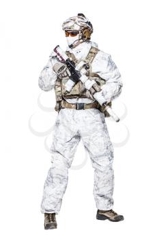 Special forces operator of Navy Seals armed with assault rifle with closed face in polarized sunglasses and military winter camo clothes designed to operations in extreme conditions. Studio shot