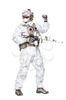 Special forces operator of Navy Seals armed with assault rifle with closed face in winter camo clothes using visual hand and arm signal to control the movement of his team. Studio shot