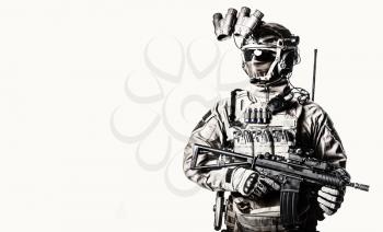 Army elite soldier with hidden behind mask and glasses face, in full tactical ammunition, equipped night vision device, radio headset, armed short barrel service rifle studio shoot on white background